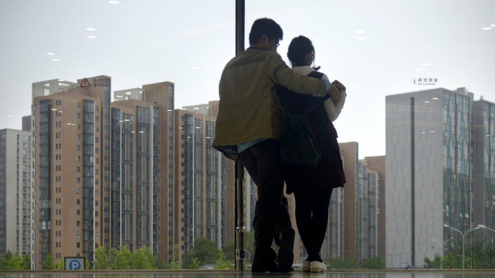 Một cặp đôi nhìn ra ngoài cửa sổ tại các dãy nhà ở Bắc Kinh
